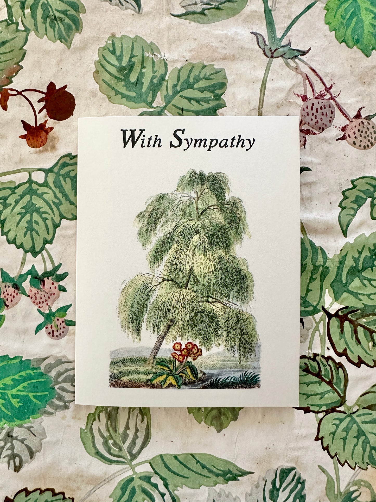 With Sympathy Willow card with riverbank illustration displayed against a coordinating antique floral backdrop, by Caldwell's Miscellaneous Fancy Goods.
