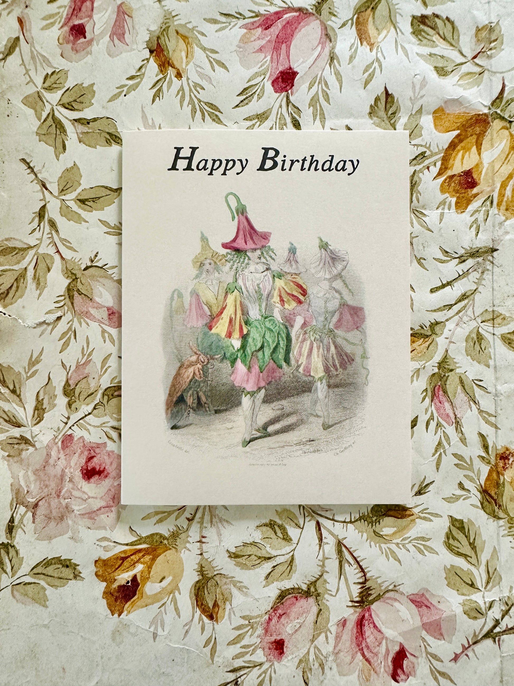 Happy Birthday Flower Hat card with parading flower fairy illustration displayed against an antique rose botanical backdrop, by Caldwell's Miscellaneous Fancy Goods.