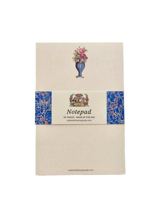 A cream-colored notepad with a decorative blue and pink floral patterned band around the middle, featuring a vase illustration and the text 'Notepad' and '50 PAGES - MADE IN THE USA'.